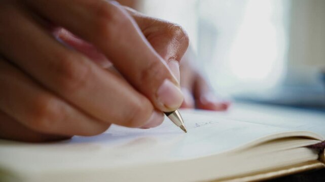 Woman's hands writing in a journal during day concept