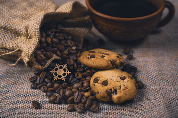 Burlap sack of coffee beans with cookies and a cup of coffee