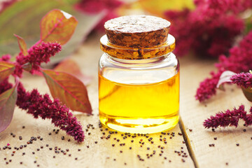 Amaranth seed oil or extract in glass bottle with  grain on wooden table, closeup, natural medicine and healthy skin and body treatment concept