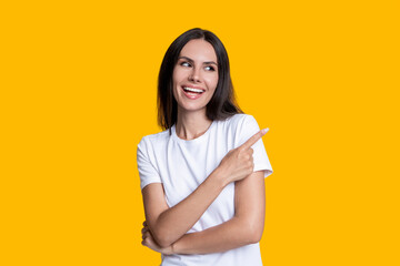 Millennial girl presenting product. Woman in white tshirt isolated on yellow. Laughing young woman point finger. Stylish female. Advertisement offer. Portrait of millennial girl. Seasonal offer