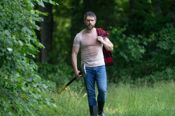 Lumberjack in woods with an ax. Lumberjack in shirt with heavy axe. Strong man in forest....
