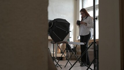 Female photographer taking photo of objects on background in photo studio with professional equipment