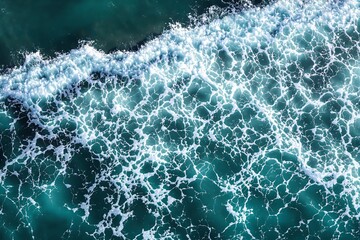 Fototapeta premium Aerial view of ocean waves creating intricate foam patterns on turquoise water surface.