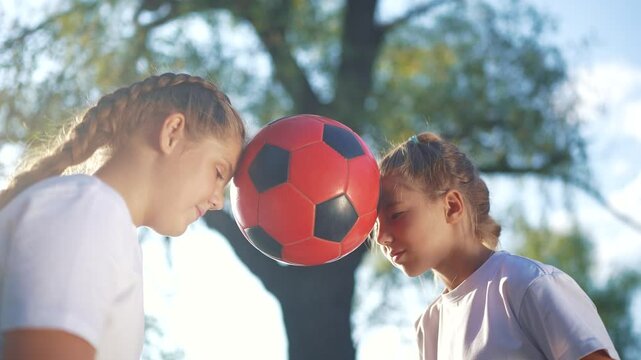 Children playing ball in the park sun glare cheerfully. Child kid game concept. Group of girls and kids playing soccer together. Group of children and girls play soccer together in a team lifestyle.