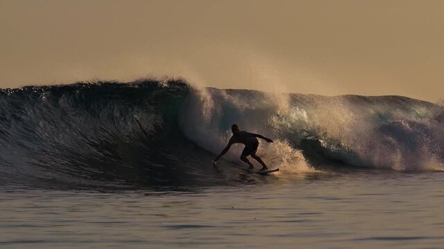 Male surfer on a wave at sunset time at Indian Ocean