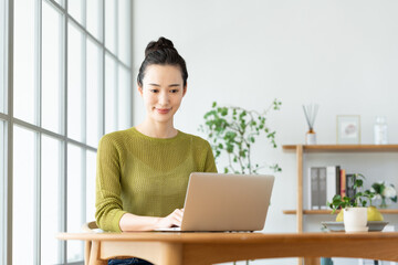 家でパソコンを使う若い女性
