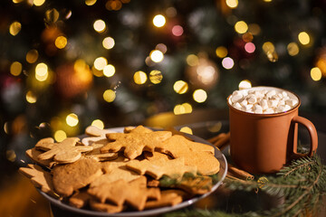 beautiful christmas gingerbread cookies and cup of cocoa with marshmallows on new year bokeh background.