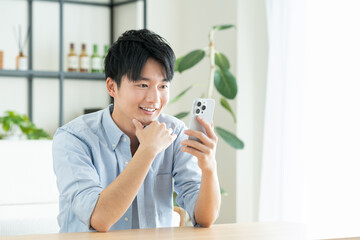 リビングでスマホを見る若い男性