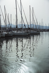 A serene marina scene featuring sailboats lined up, with tall masts reflecting in calm water, creating mesmerizing patterns.