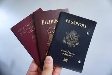 A compelling arrangement of three passports&mdash;Filipino, Polish, and American&mdash;placed side by side on a clean surface. Perfect for themes of travel, citizenship, or global identity.
