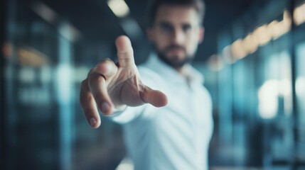 A man in white shirt extends his hand in a gesture of wanting to help or assist, blurred focus on his hand and body, modern office interior with glass walls