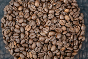 Close-up of roasted arabica coffee beans.Heap of coffee beans stacked  prepare making menu in the cafe by machine ready to be brewed into a delicious cup.Textured background.