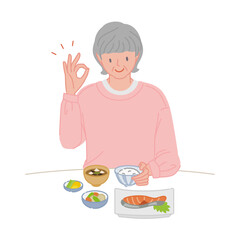 食事に手で丸のポーズをする笑顔のシニア女性（ひとり暮らし）