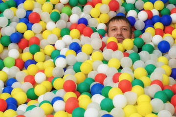 A happy man on a background of colorful plastic balls. A festive event.