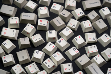 Scattered white keycaps, black on white mechanical keyboard keycaps on a matte black surface, captured from a top down perspective in a flat lay style.