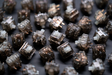 Black smoke transparent mechanical keyboard switches scattered on a matte black surface, captured from an angled top down perspective for a sleek and modern look.