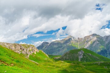 Explore the stunning landscapes of Kaprun, Austria. This photograph features lush green pastures, majestic mountains, and a serene cloudy sky, capturing the beauty of the Austrian Alps.