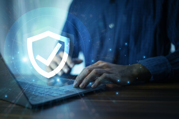 Man working on a laptop with advanced cyber security shield, ensuring the protection of sensitive...