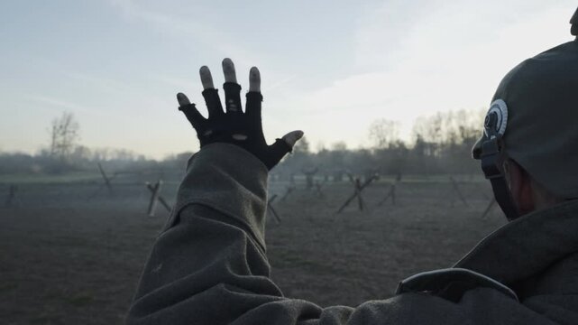 WWI scene of a German soldier emerging from a trench at dusk, hands raised, surrendering in no man's land. The dim lighting evokes a somber, tense atmosphere.