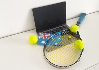 Australia flag concept with tennis racket and laptop on top view. 