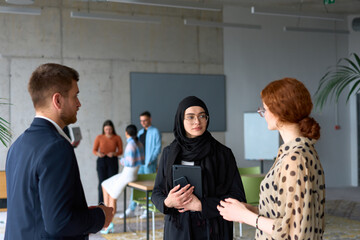 A diverse group of business professionals engages in a conversation during a work break in the...