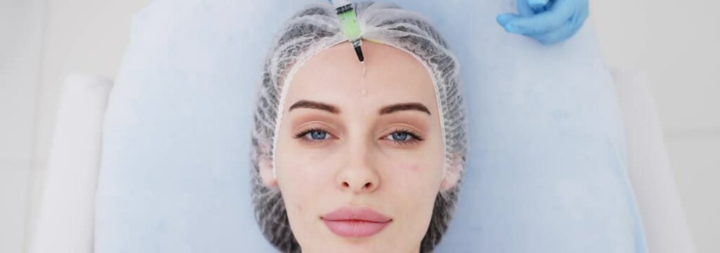 Close-up of a cosmetologist performing a facial peel on a young woman. Concept of professional care, rejuvenation, and healthy skin. Shot on anamorphic lens in 2.39