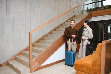 Happy couple entering the hotel pulling their luggage, vacation concept