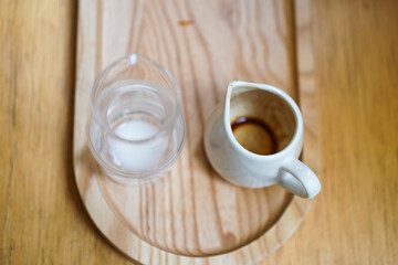 An empty milk jar and an empty espresso cup on a wooden tray with selective focused.