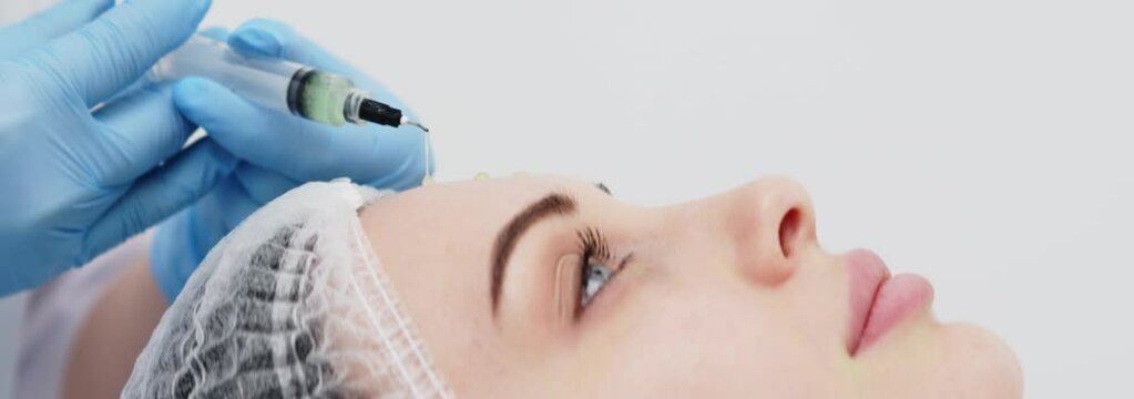 Close-up of a cosmetologist performing a facial peel on a young woman. Concept of professional care, rejuvenation, and healthy skin. Shot on anamorphic lens in 2.39