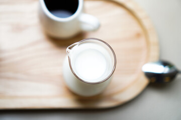 A glass jar of milk and a cup of espresso on a wooden tray with selective focused.