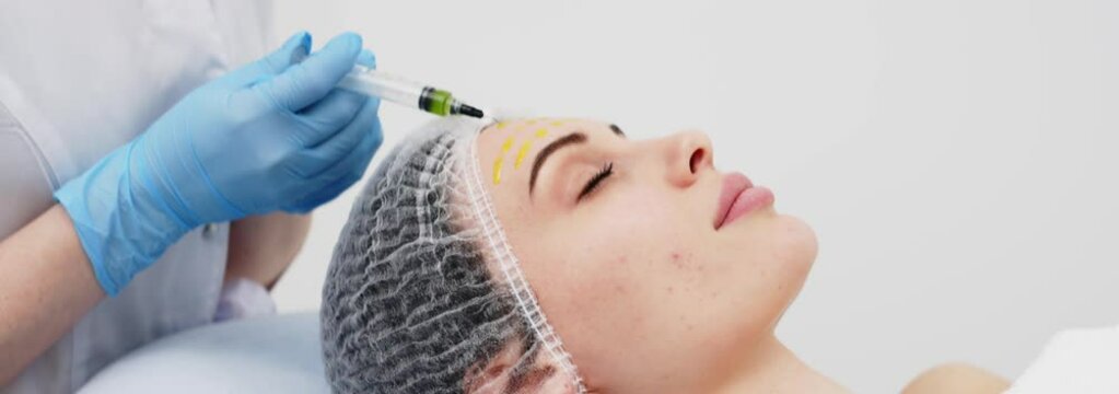 Close-up of a cosmetologist performing a facial peel on a young woman. Concept of professional care, rejuvenation, and healthy skin. Shot on anamorphic lens in 2.39