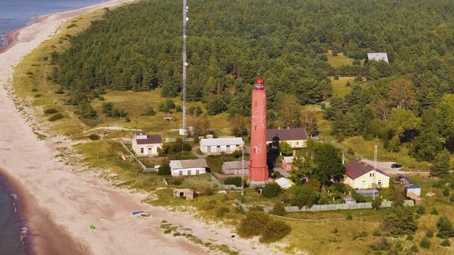 Lighthouse tower landscape, watchtower building at green forested beach aerial drone panoramic view