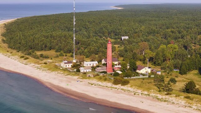 Aerial view of a lighthouse at the beach, Baltic forested area, sea shore around green wilderness
