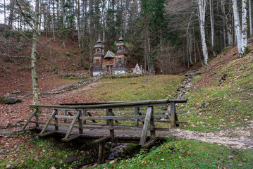 Wooden bridge leading to wooden church in autumn forest. Russian chapel, Kranjska Gora, Slovenia