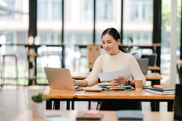 Young Asian woman doing financial accounting and taxes for a company Organizing account analysis reports Investment information Financial and tax system concepts