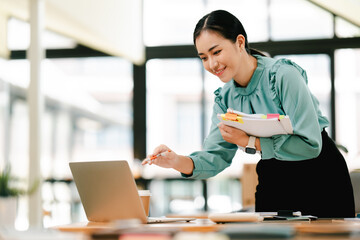 Asian female employee holding documents to check information Managing annual financial and tax analysis documents