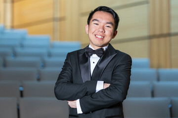 Smiling young man in a tuxedo arms crossed