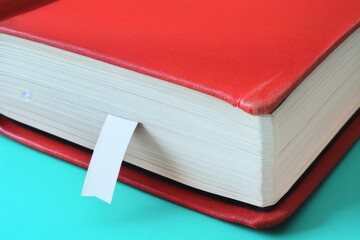 Close-up of a large red book with a bookmark, highlighting the textured cover and pages.
