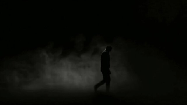 dark background. In the smoke, a person walks with his tongue pointed out.