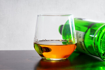 A glass of whiskey and empty bottle of whiskey on the table, close-up. Alcohol addiction.