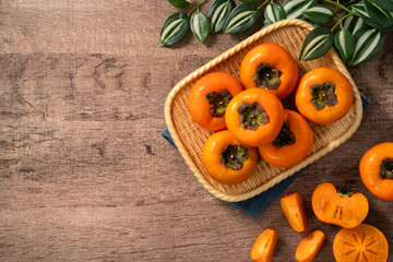 Fresh ripe persimmon fruit on wooden table background.