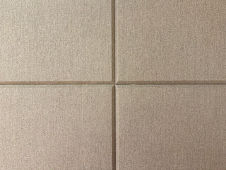 Fototapeta premium Brown beige and ivory color fabric, series of upholstered panel wall with beveled rectangular pattern. This functions as padded wall to sound insulation, or accoustic wall.