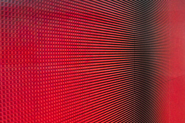 Close-up photo of video wall screen displaying red color with grid layout of pixels for digital panel LED display with mesh diodes.