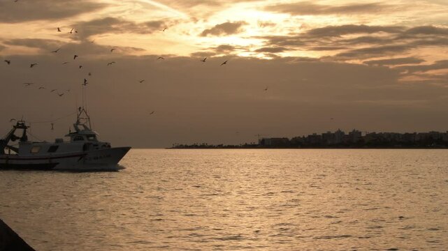 Fisher ship entering to port at sunset. Caleta de Velez, Spain