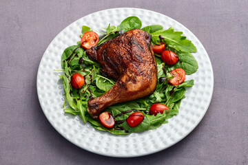 Grilled chicken legs with tomatoes and salad . Top view