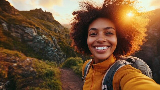 Smiling hiker taking selfie while hiking in the mountains at sunset
