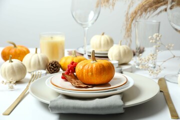 Rustic holiday table setup with plates, cutlery and autumn decorations