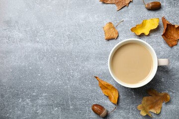 Cup of coffee with autumn leaves on a gray background