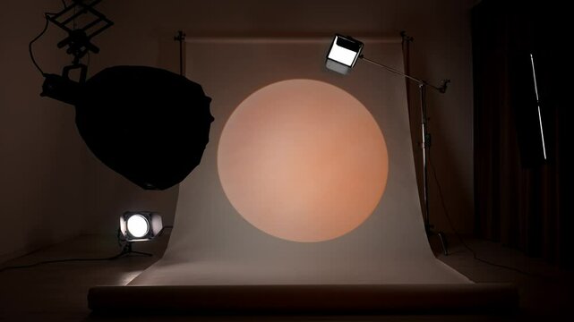 Professional studio for photo and video production filming with modern lighting equipment, large white cyclorama background, testing white orange spotlight setup.