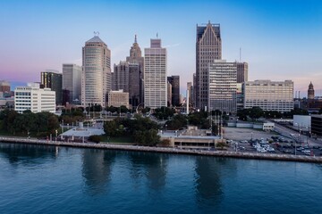 Obraz premium Detroit skyline at dawn, reflecting on the river. City buildings, park, and parking lots. DOWNTOWN, DETROIT, MICHIGAN, UNITED STATES
